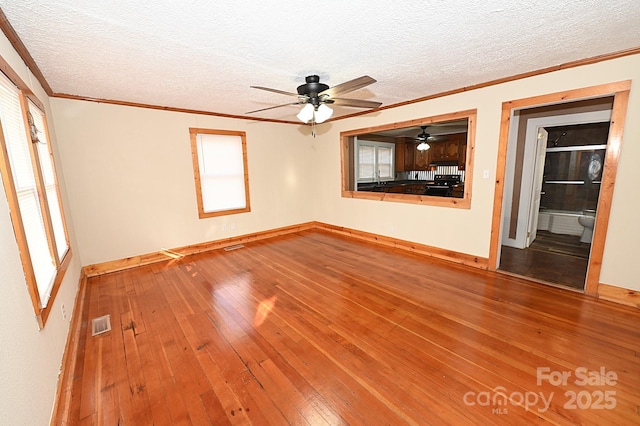 empty room with hardwood / wood-style floors, a textured ceiling, ceiling fan, and ornamental molding