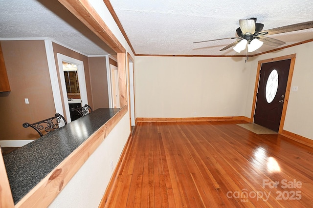 entrance foyer featuring wood-type flooring, a textured ceiling, ceiling fan, and ornamental molding