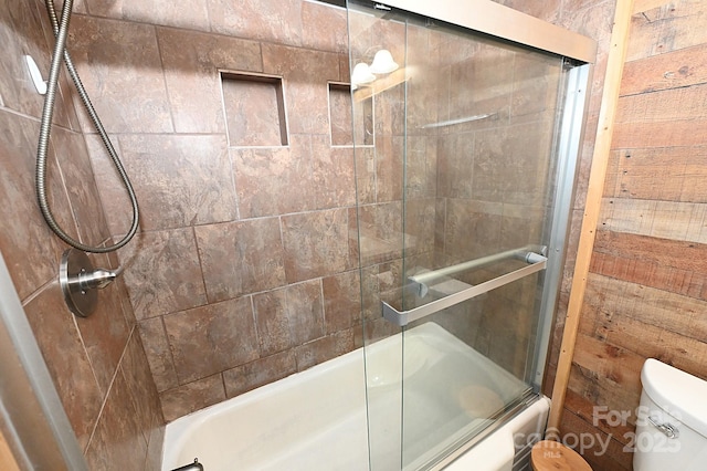 bathroom featuring wooden walls, enclosed tub / shower combo, and toilet