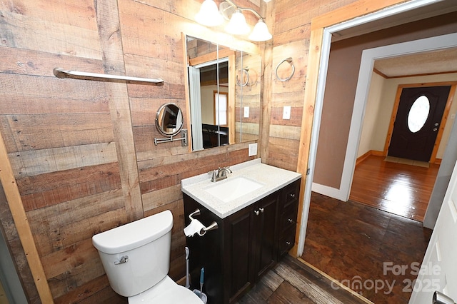 bathroom with hardwood / wood-style flooring, vanity, toilet, and wooden walls