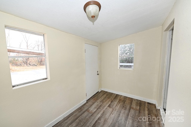 empty room with a textured ceiling, dark wood-type flooring, and vaulted ceiling