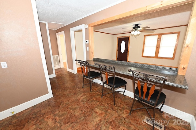 kitchen featuring a textured ceiling, ceiling fan, built in desk, and crown molding