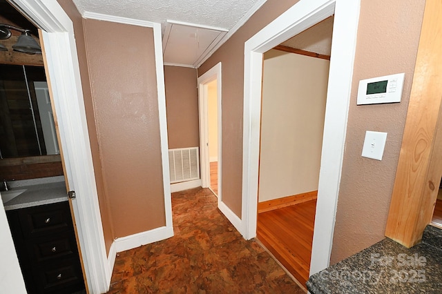 hall with a textured ceiling, ornamental molding, and sink