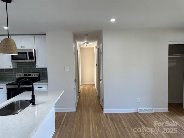 kitchen featuring white cabinetry, light stone countertops, decorative light fixtures, decorative backsplash, and appliances with stainless steel finishes