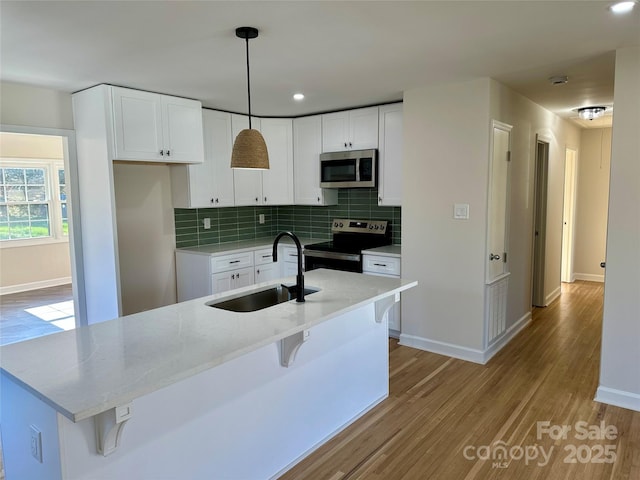 kitchen with sink, tasteful backsplash, decorative light fixtures, white cabinetry, and stainless steel appliances