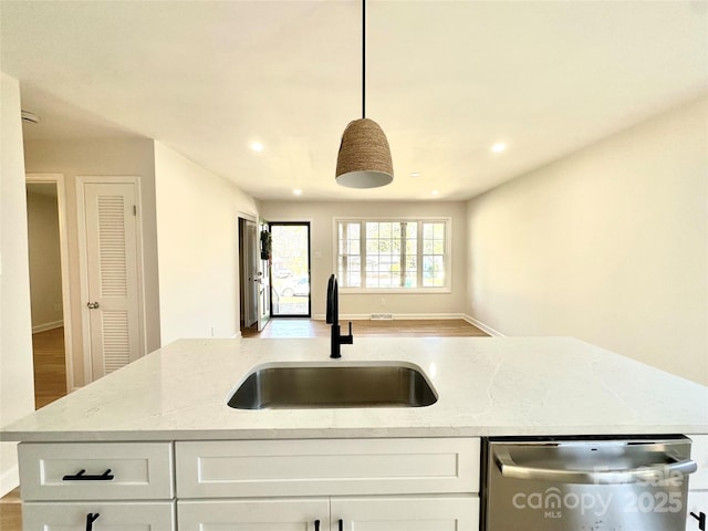 kitchen featuring dishwasher, sink, hanging light fixtures, light stone counters, and white cabinets