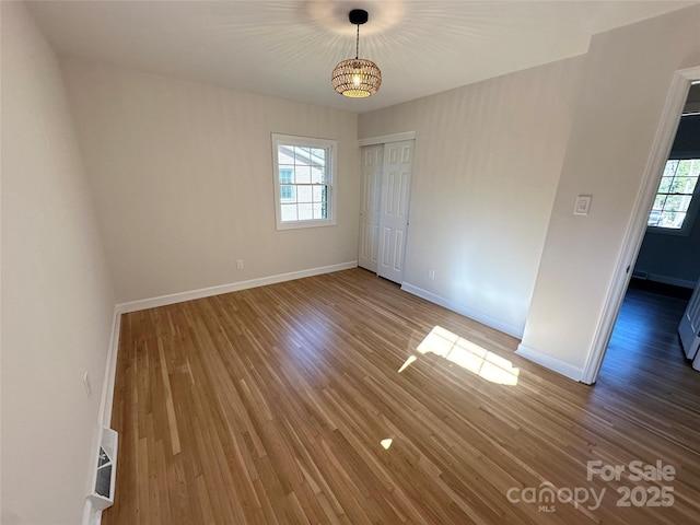 spare room featuring a notable chandelier, a healthy amount of sunlight, and wood-type flooring