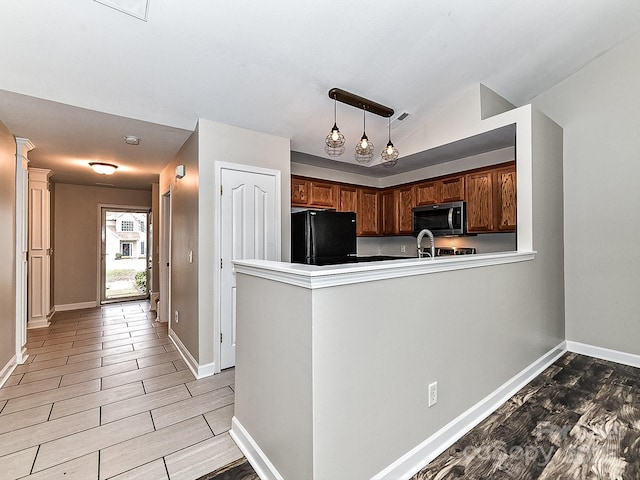 kitchen with kitchen peninsula, black fridge, sink, pendant lighting, and lofted ceiling