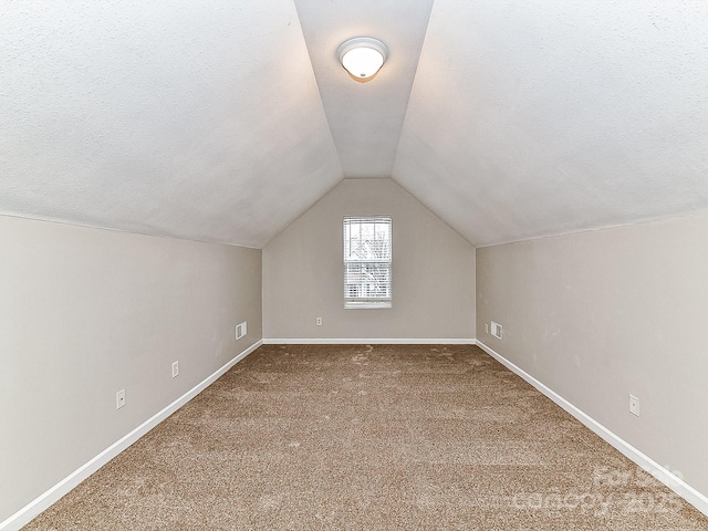 bonus room featuring carpet, lofted ceiling, and a textured ceiling