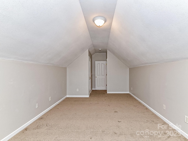 bonus room featuring lofted ceiling, light carpet, and a textured ceiling