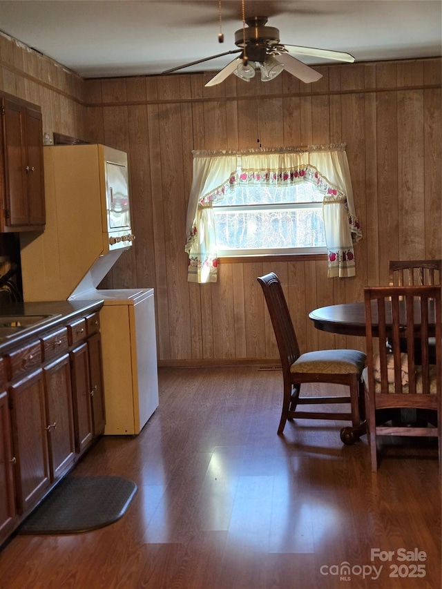 dining space featuring ceiling fan, wood walls, dark hardwood / wood-style flooring, and sink