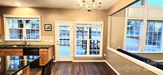 doorway to outside featuring an inviting chandelier, plenty of natural light, and sink