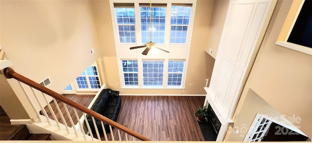 interior space with ceiling fan, hardwood / wood-style floors, and a towering ceiling