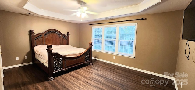 bedroom with dark hardwood / wood-style flooring, a tray ceiling, ceiling fan, and crown molding