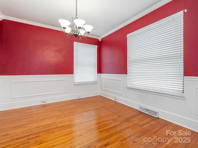 unfurnished room with a chandelier, hardwood / wood-style flooring, and ornamental molding