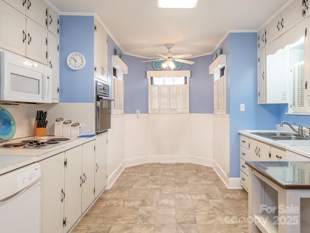 kitchen with white cabinetry, sink, ceiling fan, crown molding, and white appliances