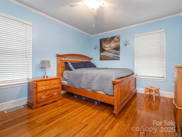 bedroom with ceiling fan, wood-type flooring, ornamental molding, and multiple windows