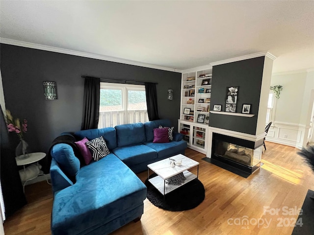 living room with a multi sided fireplace, built in features, and crown molding