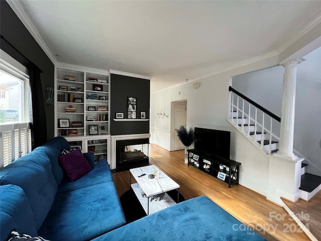 living room featuring hardwood / wood-style floors, built in shelves, crown molding, and a wealth of natural light