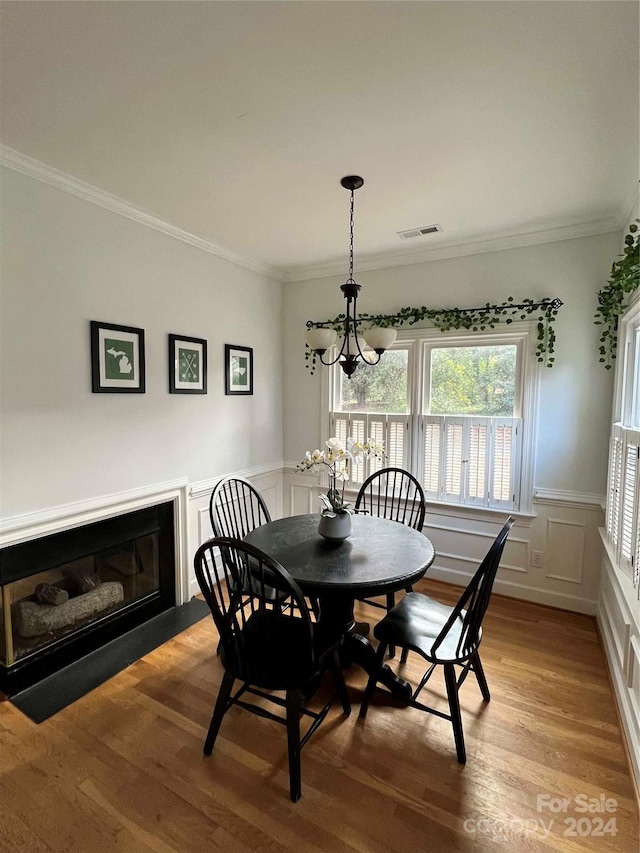 dining room with an inviting chandelier, ornamental molding, and light hardwood / wood-style flooring