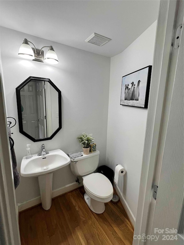 bathroom with wood-type flooring, toilet, and sink