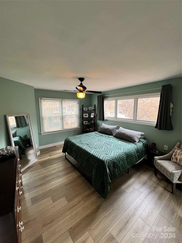 bedroom featuring ceiling fan, light wood-type flooring, and multiple windows