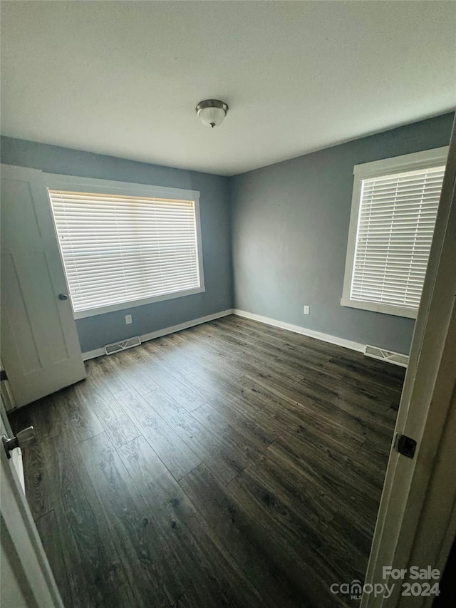 unfurnished room with dark wood-type flooring