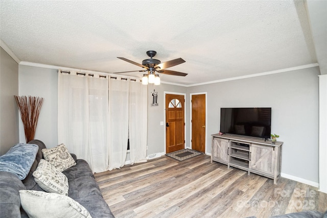 living room featuring hardwood / wood-style flooring, a textured ceiling, ceiling fan, and ornamental molding