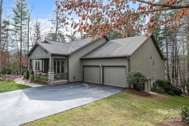 view of front of house with covered porch, a garage, and a front lawn