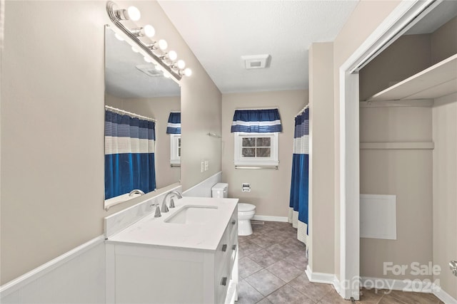 bathroom featuring a textured ceiling, vanity, toilet, and tile patterned floors