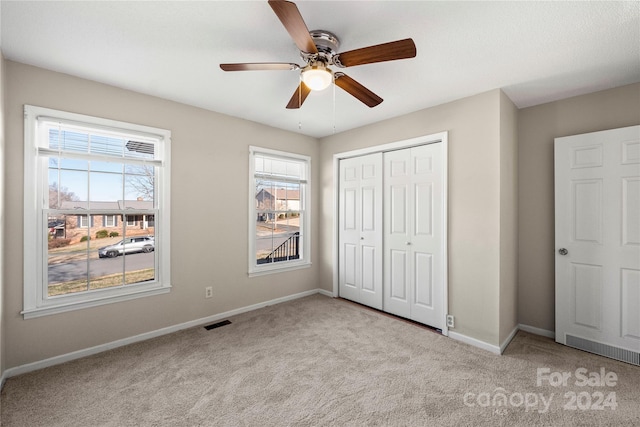 unfurnished bedroom featuring ceiling fan, a closet, and light colored carpet