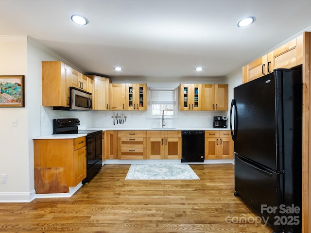 kitchen featuring sink, decorative backsplash, black appliances, and light wood-type flooring