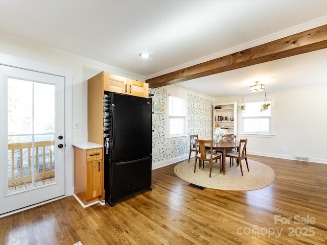 dining area featuring crown molding, a healthy amount of sunlight, hardwood / wood-style floors, and beam ceiling