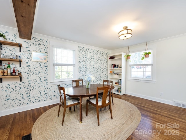 dining space with dark wood-type flooring, ornamental molding, and plenty of natural light