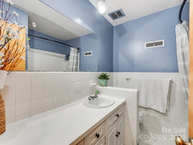 bathroom with a shower with curtain, vanity, tile walls, and toilet