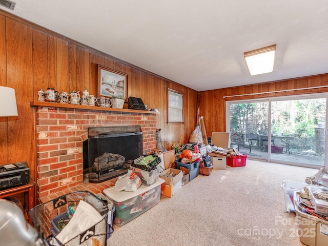 carpeted living room featuring wooden walls and a fireplace