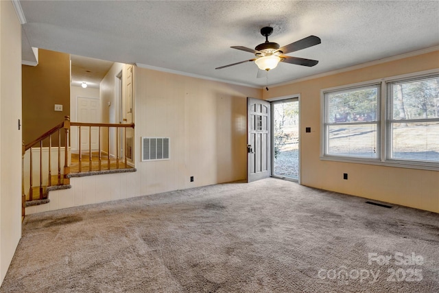 unfurnished living room with a textured ceiling, ceiling fan, carpet flooring, and crown molding