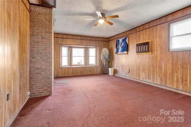 carpeted empty room featuring an AC wall unit, ceiling fan, a healthy amount of sunlight, and a textured ceiling