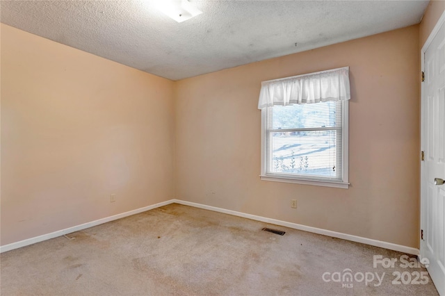 spare room with light colored carpet and a textured ceiling