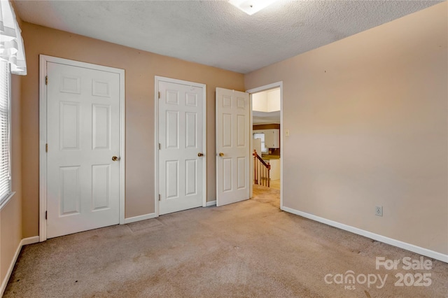 unfurnished bedroom featuring a textured ceiling and light colored carpet