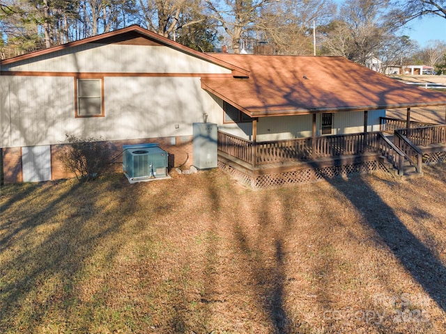 rear view of property featuring a yard, central AC, and a wooden deck