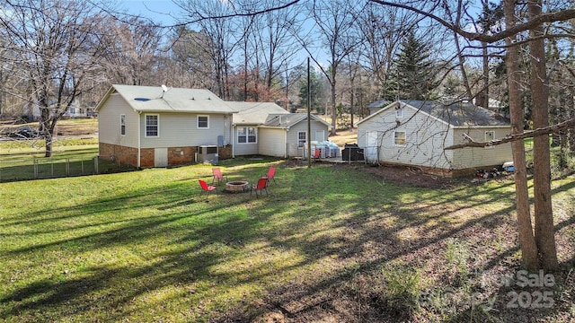 rear view of house featuring a fire pit, central AC unit, and a lawn