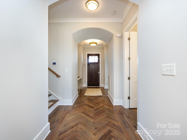 foyer with arched walkways, crown molding, stairway, and baseboards