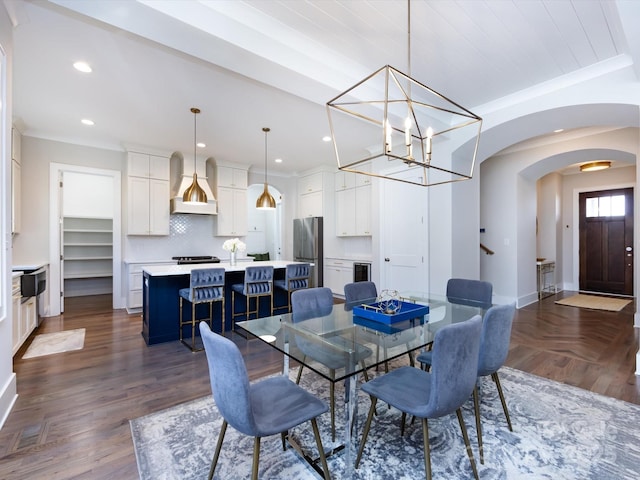 dining area with baseboards, arched walkways, dark wood finished floors, crown molding, and recessed lighting