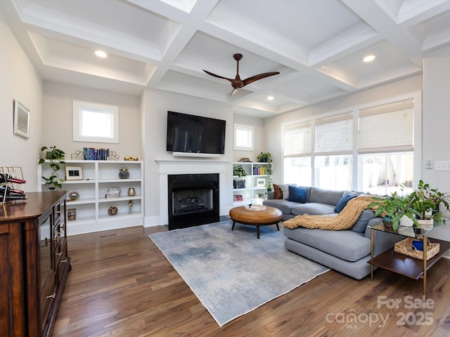 living area with coffered ceiling, ceiling fan, a fireplace with flush hearth, dark wood-type flooring, and beamed ceiling