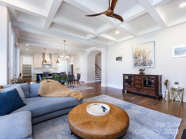 living area featuring baseboards, arched walkways, dark wood finished floors, and beam ceiling