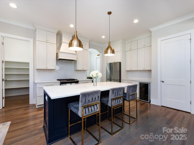 kitchen with appliances with stainless steel finishes, wine cooler, custom range hood, and crown molding