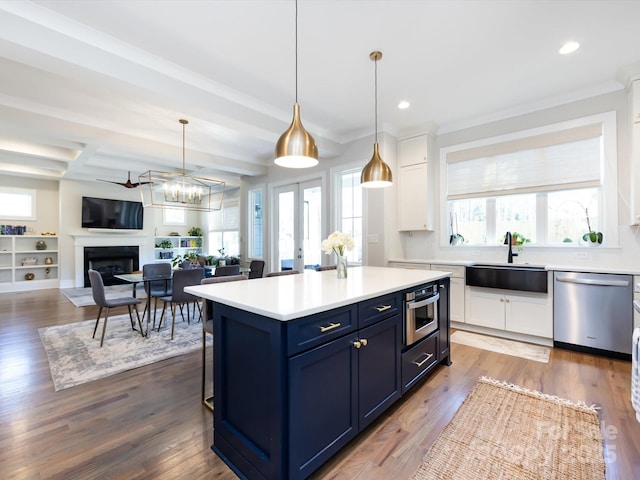 kitchen featuring dark wood finished floors, stainless steel appliances, blue cabinetry, white cabinetry, and a sink