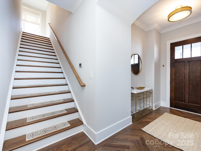 entryway with ornamental molding, stairway, and baseboards