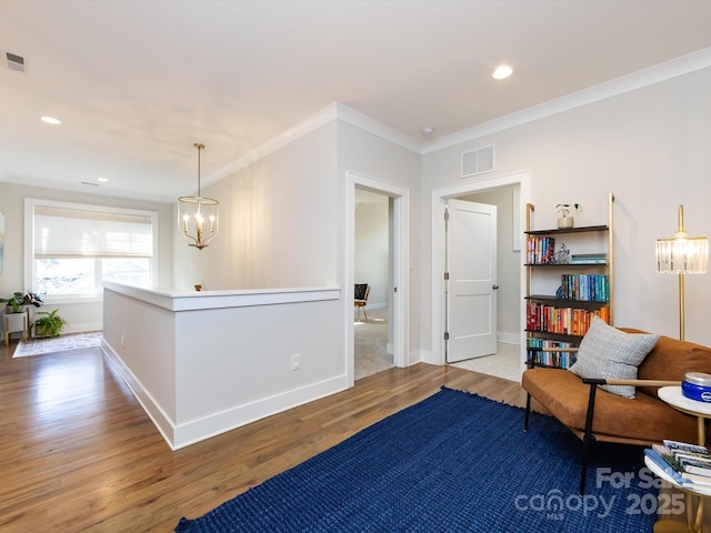 living area featuring visible vents, crown molding, baseboards, and wood finished floors